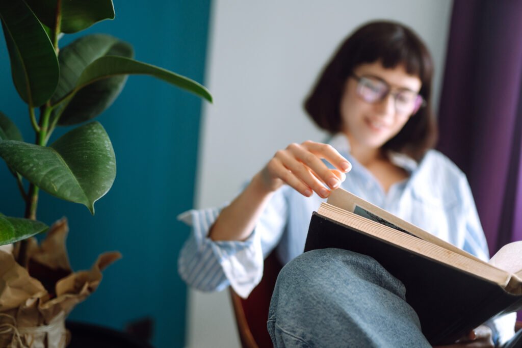 a young woman reads a book at home, sitting in her living room. concept of rest, relaxation.